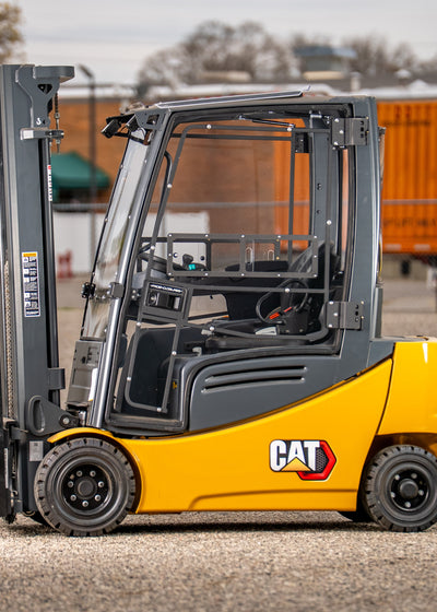 Yellow and gray Caterpillar forklift on a concrete surface with a blurred background